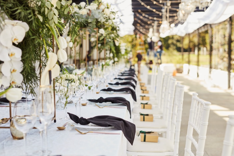 Banquet table set with white chairs and gold accents